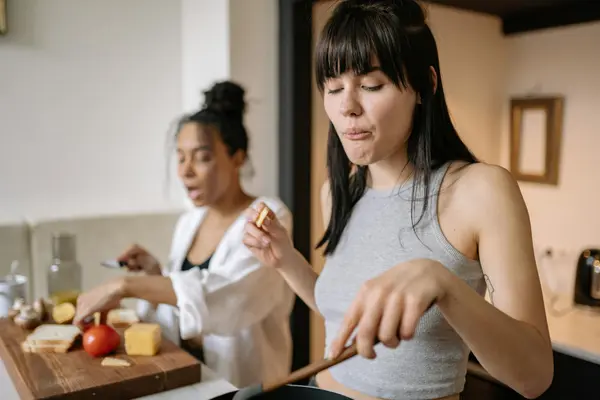 A coliving kitchen at dinnertime with mixed nationalities cooking and laughing together