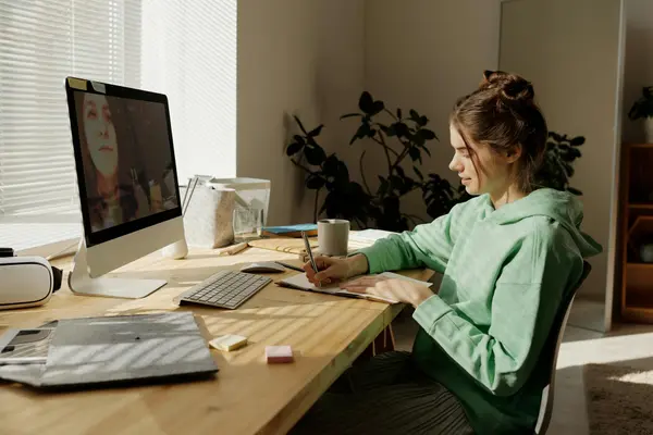 A remote worker on a video call at a desk in a Laureles coliving with bright morning light