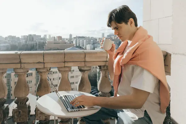 A digital nomad working from a sunlit coliving rooftop with laptop, notebook and Mexican coffee
