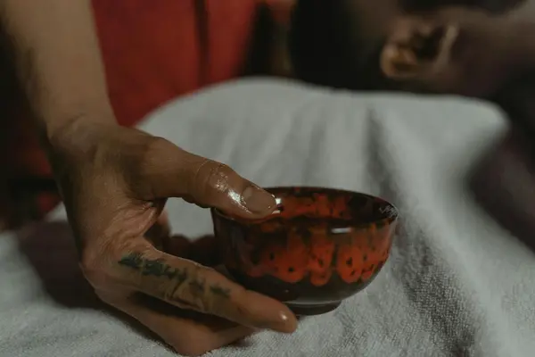 Bowl of pozole and hand holding a cup of pox at a wooden bar in San Cristóbal