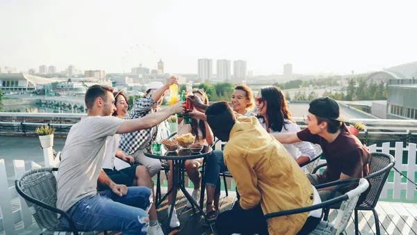 Group of digital nomads laughing on a rooftop terrace in Medellín at sunset with the valley and brick buildings
