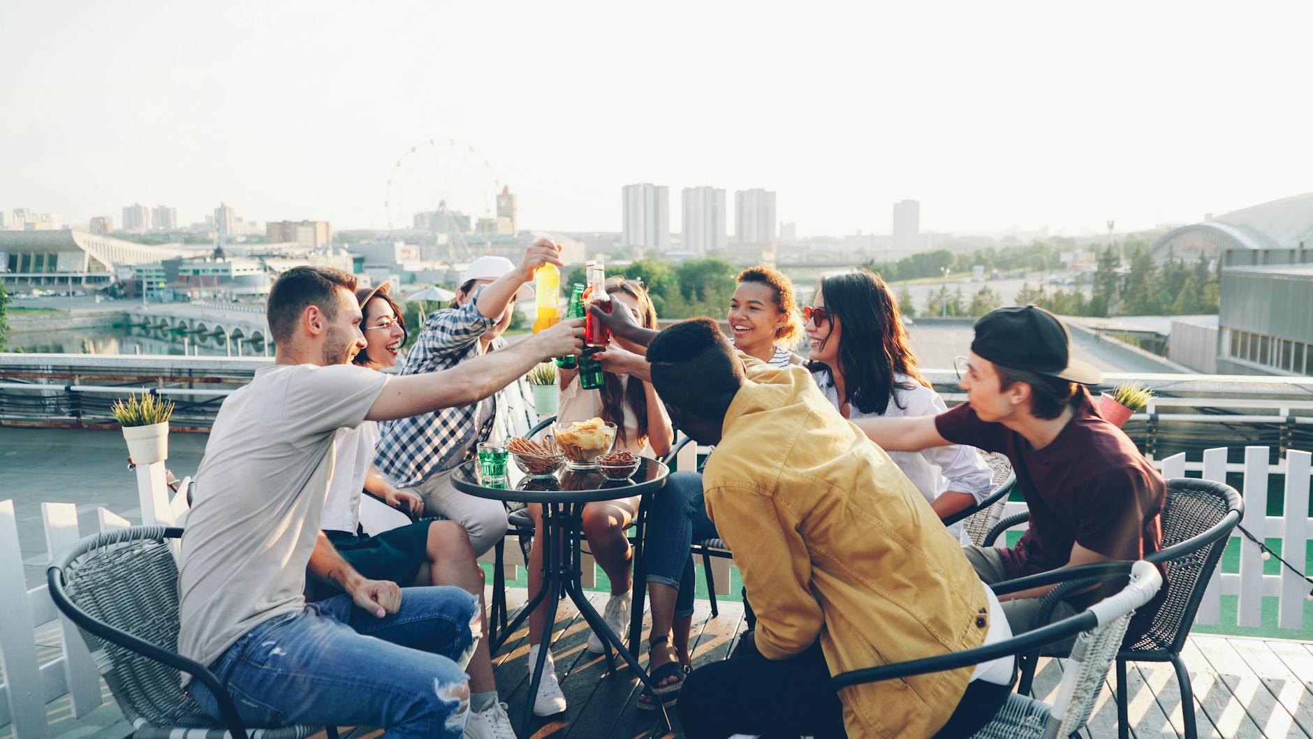 Group of digital nomads laughing on a rooftop terrace in Medellín at sunset with the valley and brick buildings