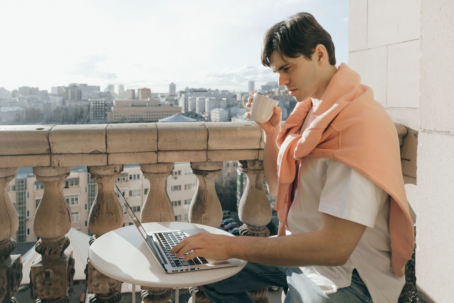 A digital nomad working from a sunlit coliving rooftop with laptop, notebook and Mexican coffee